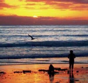 A crowded summer beach scene at sunset in San Diego, California