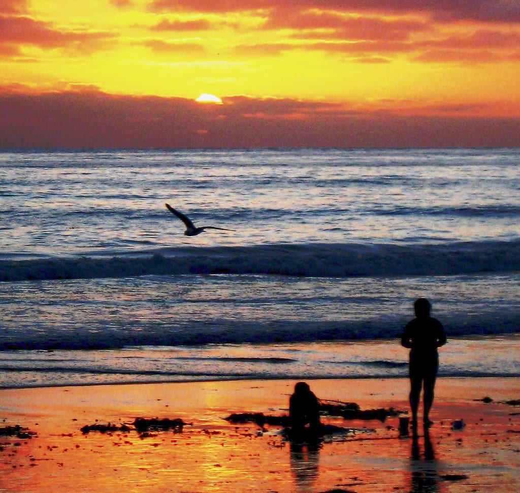 A crowded summer beach scene at sunset in San Diego, California